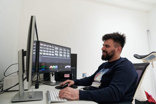 professional video editor enhancing digital footage using specialized software. Expert videographer in home office workspace editing on dual screen workstation computer desktop workplace