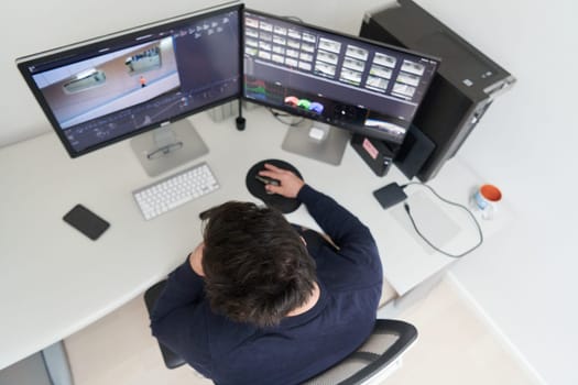 professional video editor enhancing digital footage using specialized software. Expert videographer in home office workspace editing on dual screen workstation computer desktop workplace