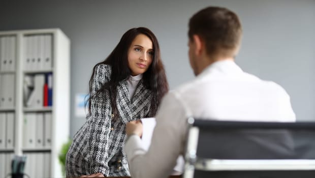 Business woman stands leaning on table in front man. Distinctive features female leader. Increase motivation and self-esteem employees. Personal conversations and encouragement subordinates