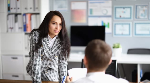 Woman puts pressure on man sitting in front her. Behavior subordinates when they are led by woman. Supervisor expresses strong approval to employee. Flexible approach to subordinates