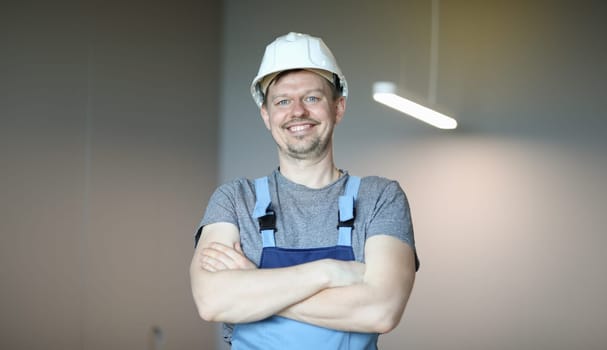 Happy man in work clothes folded arms over chest. Builder rejoices at opportunity to work during pandemic. Good physical loader. Self-isolation electric and home repair during quarantine
