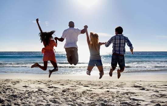 Jump, beach and back of friends holding hands on holiday vacation together in summer at sea. Group, happy or excited men with women in fun celebration of freedom by ocean, sand, nature for travel.