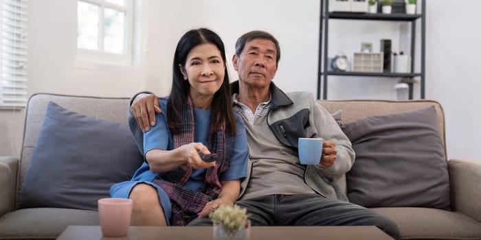Senior couple watching tv and sofa in relax for movie or series in living room at home. Elderly man and woman with coffee and remote together for changing channel and online entertainment.