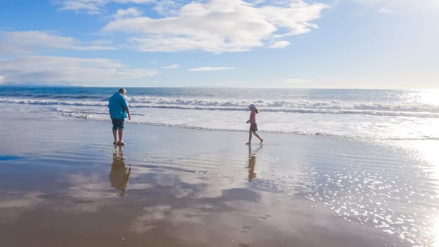 In California, a father and daughter share a serene winter walk along the deserted sands of El Capitan State Beach.