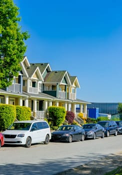 Street of townhomes with cars parked along the road on summer season in British Columbia