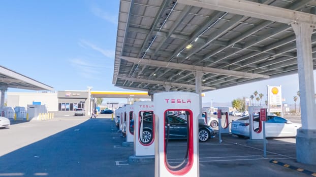 Baker, California, USA-December 3, 2022-During the day, a Tesla vehicle is seen charging at a Tesla Supercharging station, utilizing the high-speed charging infrastructure for convenient and efficient electric vehicle refueling.