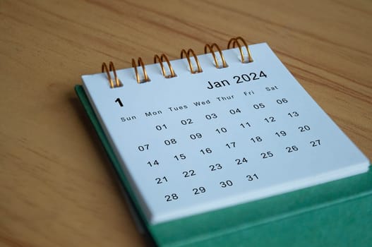 Close up side view of January 2024 calendar on wooden desk. Calendar concept.