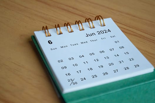 Close up side view of June 2024 calendar on wooden desk. Calendar concept.