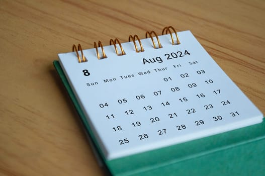 Close up side view of August 2024 calendar on wooden desk. Calendar concept.