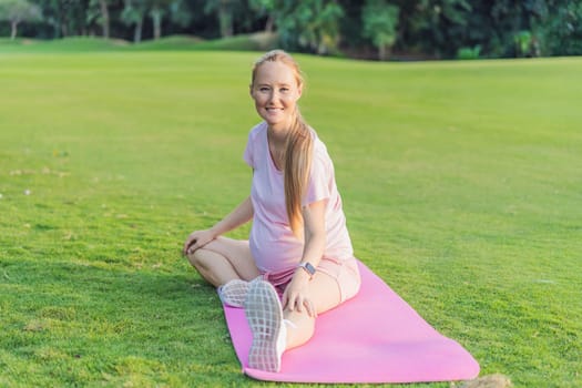 Energetic pregnant woman takes her workout outdoors, using an exercise mat for a refreshing and health-conscious outdoor exercise session.