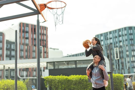 Happy father and teen daughter outside at basketball court