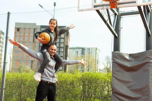 Happy father and teen daughter outside at basketball court