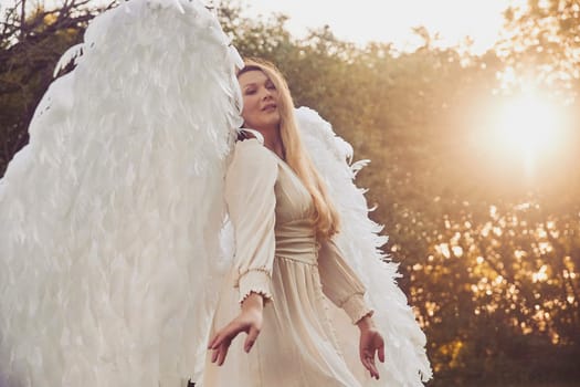 Beautiful girl dressed as an angel in the evening garden.