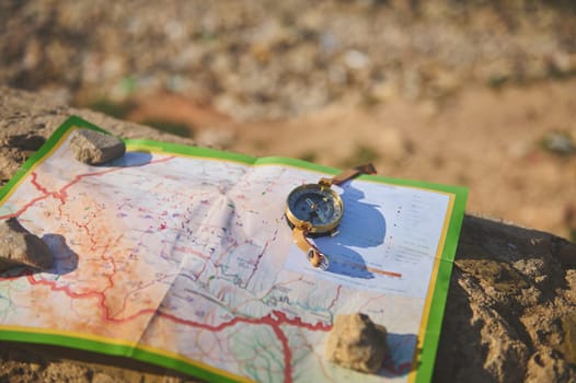 Close-up of an old golden compass and geographic map on a rock. Trip. Tourism. Travel concept. Using navigational equipment to check and search direction while e discovering new travel destinations