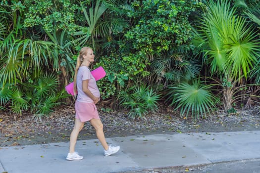 Energetic pregnant woman takes her workout outdoors, using an exercise mat for a refreshing and health-conscious outdoor exercise session.