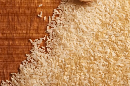 Close-up of uncooked white rice grains on a brown surface.