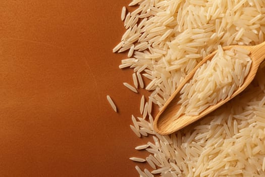 Uncooked white rice on a wooden spoon with brown background