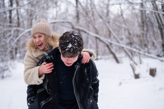 A young couple walks in the park in winter. Guy and girl hugging outdoors