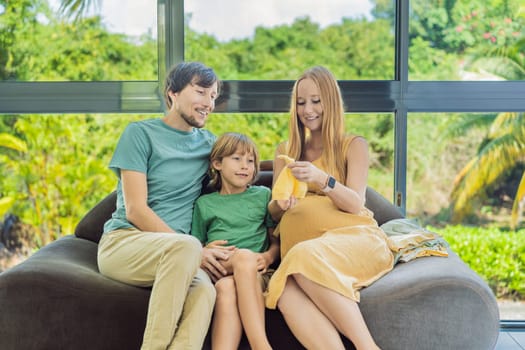 Heartwarming family moment as expectant mom, dad, and son joyfully browse through newborn baby's clothes, eagerly anticipating the arrival of a new family member.