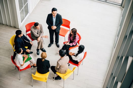 Top view of a busy office with diverse colleagues collaborating. A businesswoman and businessman sit around a conference, offering copy space for your business meeting concept. Teamwork in progress.