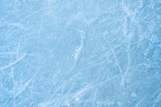 Icy background on rink with visible traces of skating, showcasing the essence of winter sport. Texture of ice on skating rink visible from top view, displaying sheet of scratched ice.