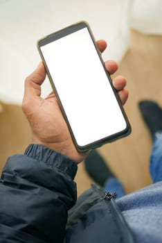 holding smart phone with white screen and home interior decoration on table .