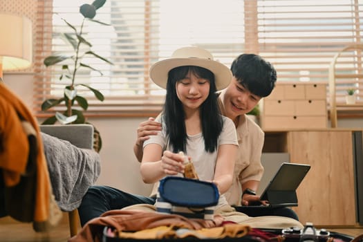 Loving young couple packing clothes into travel bag, getting ready for their holiday trip.