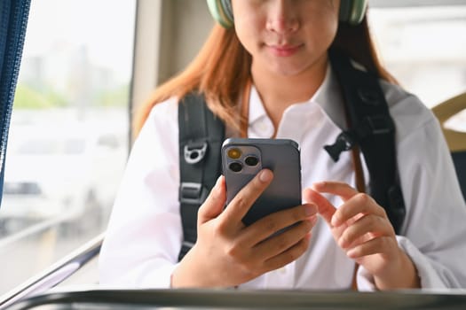 Cropped shot of young woman using mobile phone in public transportation.