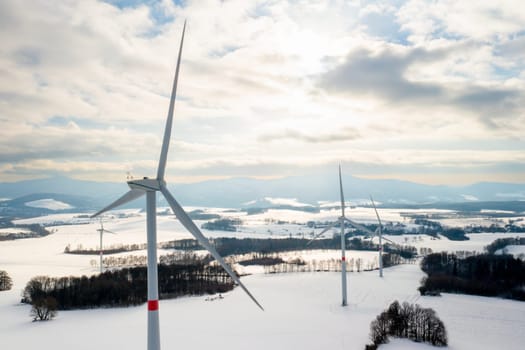 Panoramic view of wind turbines in a field in winter at sundown. Green energy producing concept