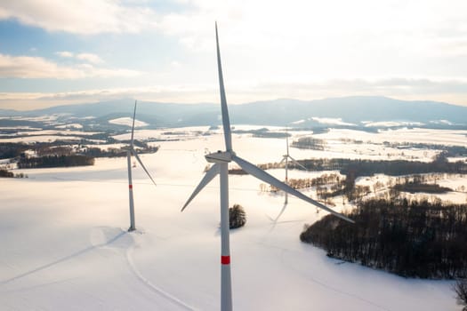 Panoramic view of wind generators in a winter field at dusk. Production of green energy.