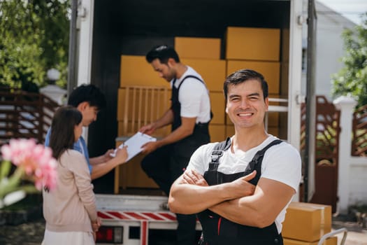 A cheerful mover captured in a portrait unloads boxes into a new home from a truck. These workers ensure efficient moving bringing happiness. Moving day concept