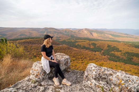 woman on mountain peak looking in beautiful mountain valley in autumn. Landscape with sporty young woman, blu sky in fall. Hiking. Nature.