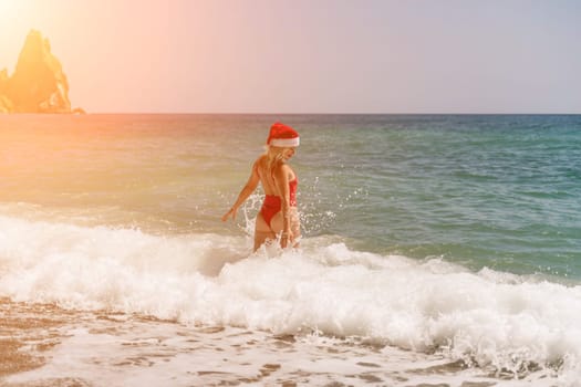 A woman in Santa hat on the seashore, dressed in a red swimsuit. New Year's celebration in a hot country.