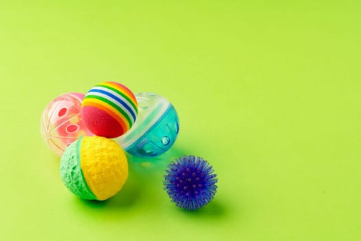 Colorful pet toys balls on green background close up