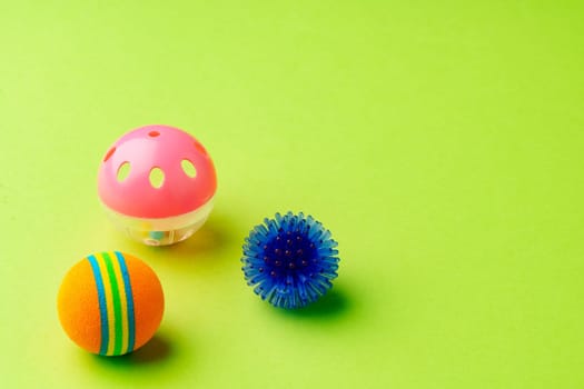 Colorful pet toys balls on green background close up