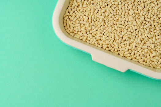 Pet litter box with bio filler on green background close up