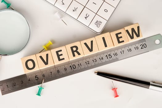 OVERVIEW text of non-wooden cubes next to a calculator, pen, measuring ruler, magnifying glass on a white background