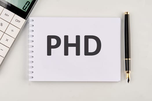 PHD the inscription on the notebook next to the calculator and pen