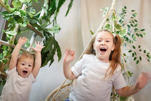 Very Happy and joyful girls. Sisters in chair and having fun. Female Preschooler and teenager playing and relaxing in room