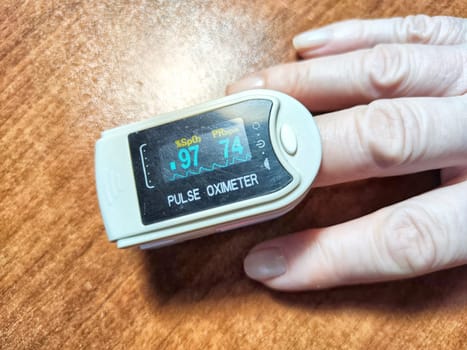 Close up of hand with a pulse oximeter on the finger.