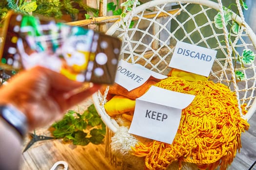 The blogger takes off stacks of clothes and signs with the words save, donate, throw away on his cell phone. The concept of clutter, a debacle for a blog and a post. Partial focus