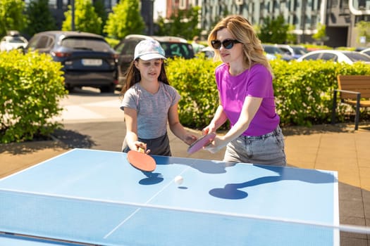 Young woman with her daughter playing ping pong in park.