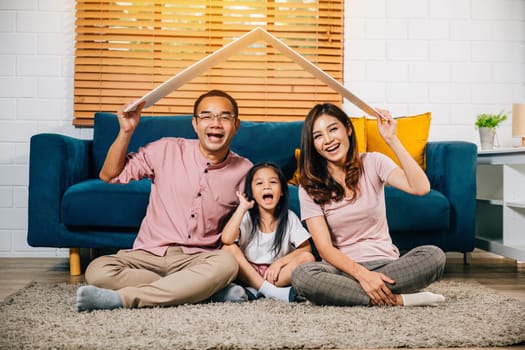 Smiling family including mother father and kids with cardboard roof on sofa embodies the concept of housing and relocation. Their security and joy are evident making every step a worthwhile investment