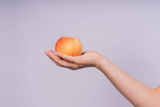 Studio portrait of a happy young woman, smiling, holding ripe nectarines in hands