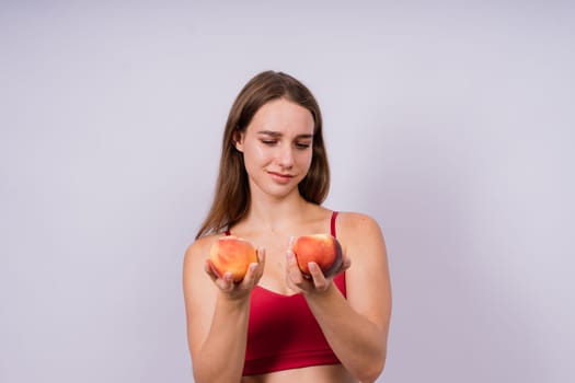 Studio portrait of a happy young woman, smiling, holding ripe nectarines in hands