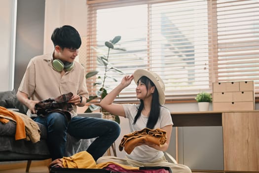 Beautiful young couple preparing for vacations and packing suitcases in living room.