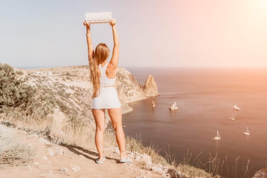 Woman travel sea. Young Happy woman in a long red dress posing on a beach near the sea on background of volcanic rocks, like in Iceland, sharing travel adventure journey