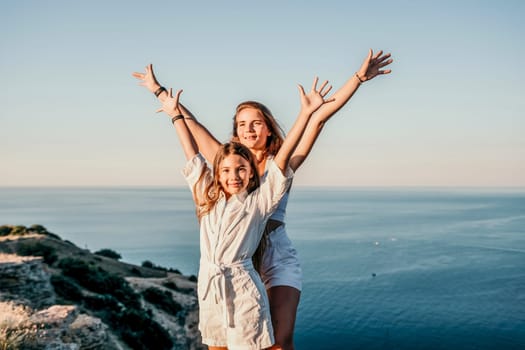 Close up portrait of mom and her teenage daughter hugging and smiling together over sunset sea view. Beautiful woman relaxing with her child.