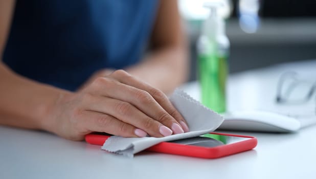Woman wiping cell phone screen with antiseptic napkin closeup. Sanitary standards of conduct during covid-19 pandemic concept