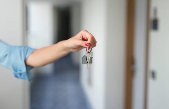 Female hand with red manicure holding house keys closeup. Buying property concept